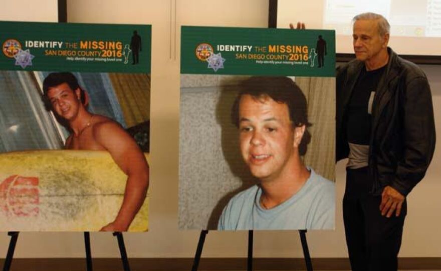 Milan "John" Nellans stands in front of photographs of his son John Patrick, or "JP," who went missing in 1985 in this undated photo.