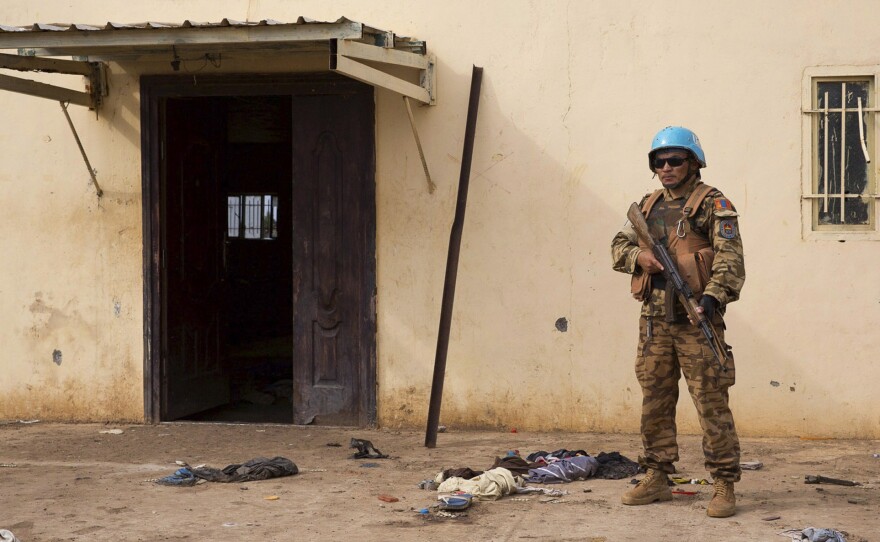 A United Nations peacekeeper stands guard near the scene where about 200 civilians were reported killed during a recent attack in the town of Bentiu.