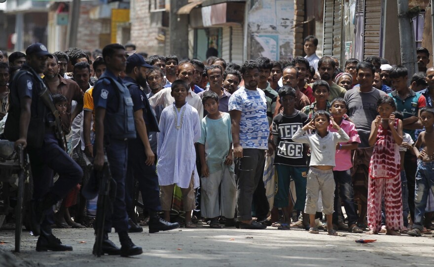 Bangladeshis gather near the scene of the raid Saturday in Narayanganj, on the outskirts of Dhaka.