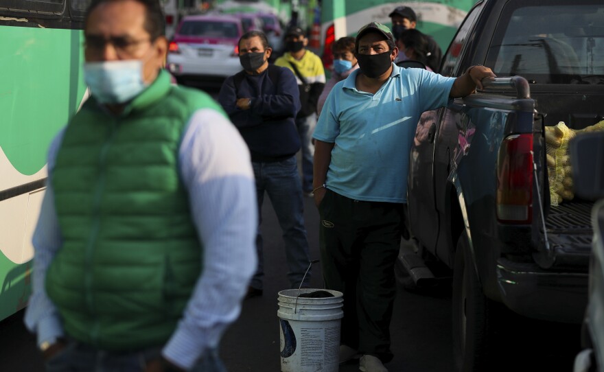 Commuters wait to board buses in Mexico City on Monday.