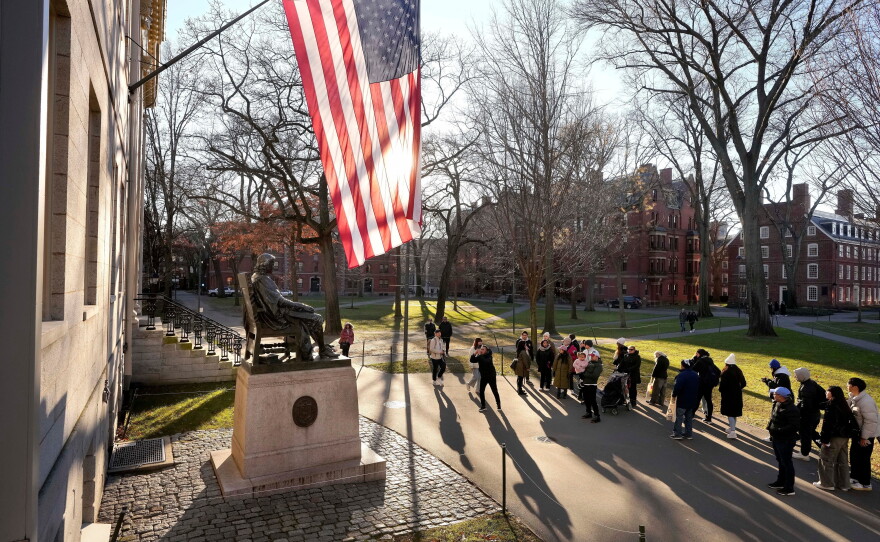 FILE - People take photos near a John Harvard statue, left, on the Harvard University campus, Jan. 2, 2024, in Cambridge, Mass.