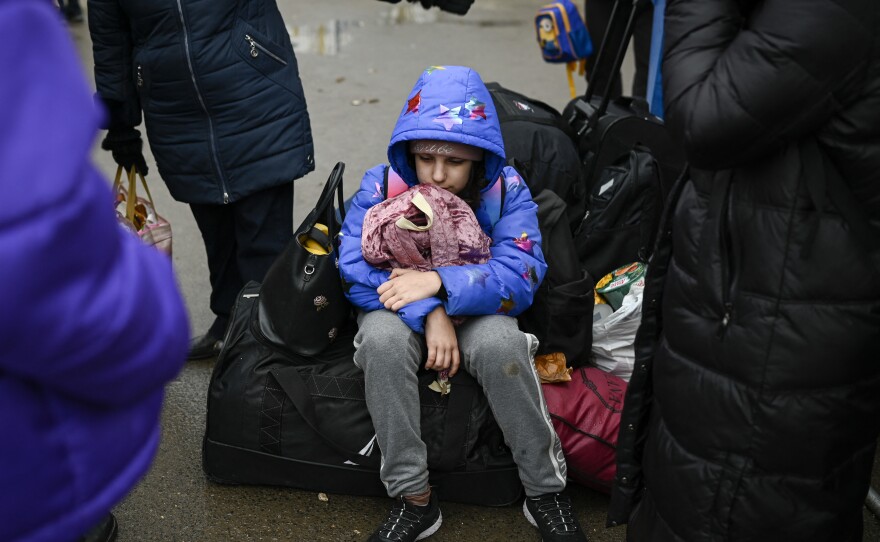 A child fleeing the conflict in Ukraine rests on a suitcase after crossing the Moldova-Ukraine border checkpoint near the town of Palanca on Wednesday, seven days after Russia's invasion of Ukraine.