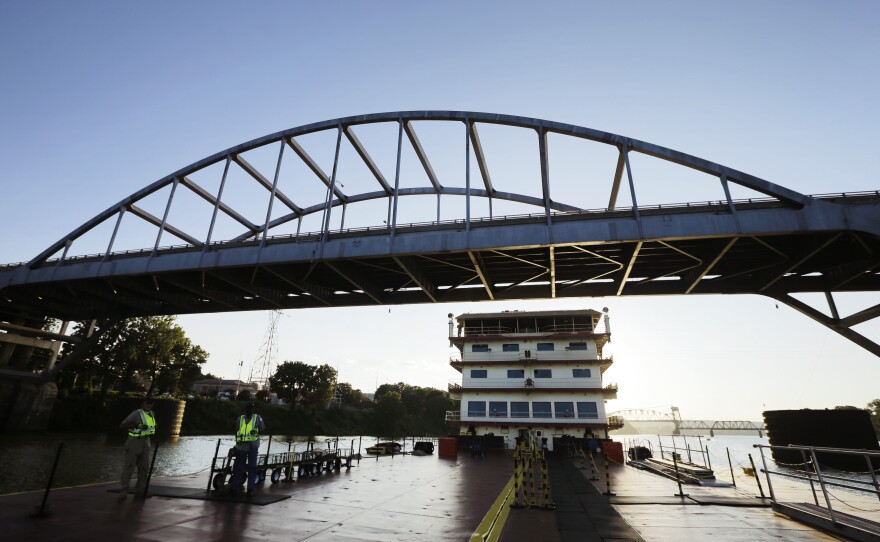 The sun sets behind the U.S. Army Corps of Engineers towboat Mississippi as it passes beneath part of the Broadway Street Bridge over the Arkansas River in 2014. Authorities tried to bring down the bridge on Tuesday. They really, really tried.