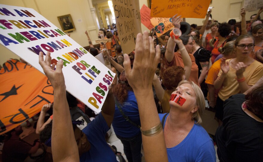 Opponents — dressed in blue — and supporters — wearing orange — of abortion rights rally in the State Capitol rotunda Friday before the vote on a set of sweeping abortion restrictions.