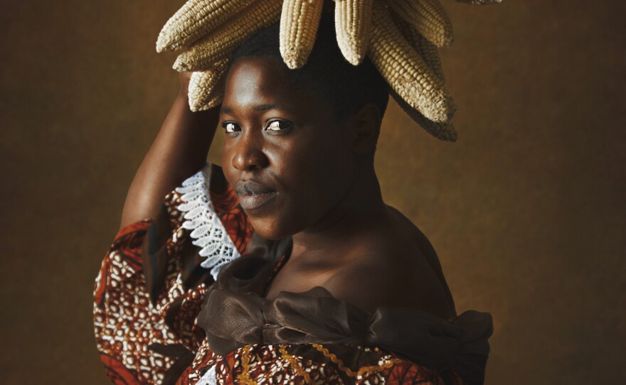 <em>Lady With Corn. </em>Kudita highlights corn in a headdress. A basic grain in Zimbabwe for centuries it still shapes daily meals.