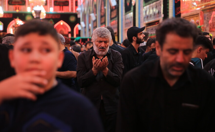 A pilgrim raises his hands in prayer amid the crowds inside the Imam Hussein Shrine in Karbala during the Arbaeen commemoration.