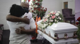 In this July 21, 2020, file photo, Darryl Hutchinson, facing camera, is hugged by a relative during a funeral service for Lydia Nunez, who was Hutchinson's cousin at the Metropolitan Baptist Church in Los Angeles. Nunez died from COVID-19.