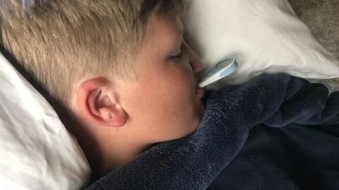 A boy with the flu taking his temperature at his home in San Diego, Feb. 14, 2018.