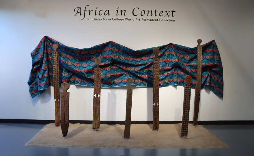 Seven vigango pieces are shown in a Jan. 2023 photo, installed in a sandy environment in the "Africa in Context" exhibition at Mesa College Art Gallery.