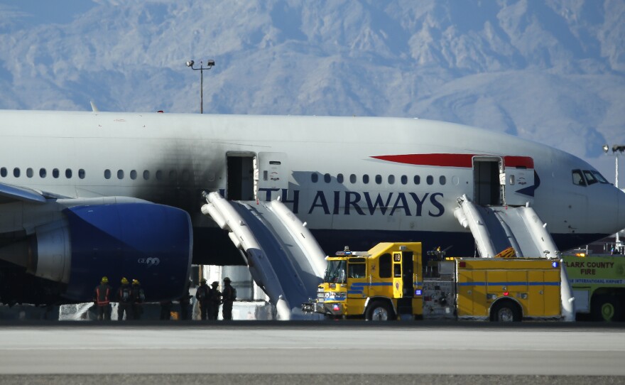 Firefighters stand by the charred plane that caught fire at McCarran International Airport today in Las Vegas.
