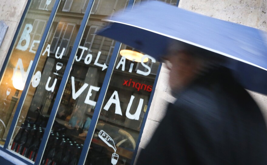 A man walks past a bar advertising Beaujolais Nouveau Day in Paris. Many bars and restaurants were sparsely crowded on a day that normally is a time to celebrate.