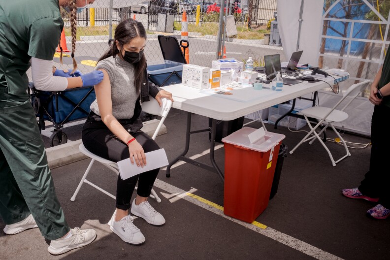 A girls receives the Pfizer COVID-19 vaccine at the Family Health Centers of San Diego in Barrio Logan, May 13, 2021. 