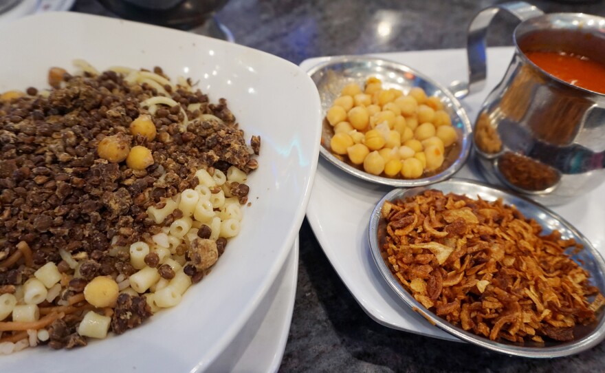 Cheap and filling, hearty plates of rice with lentils and pasta are topped with chickpeas, tomato sauce and fried onions.