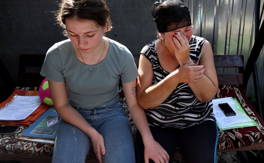 Oleksandr's sister Anya Breus comforts their mother, Oksana, as she cries.