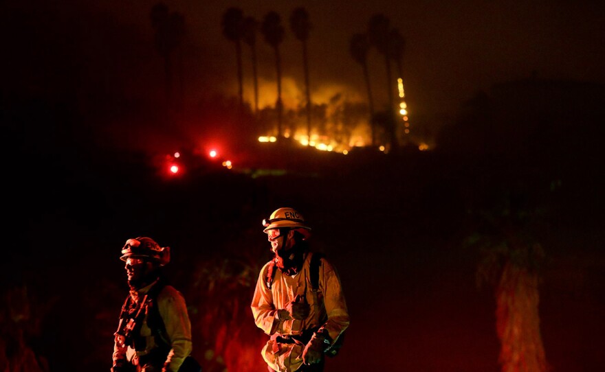 Fire crews look on as they fight a wildfire Thursday, Dec. 7, 2017, in Bonsall, Calif.