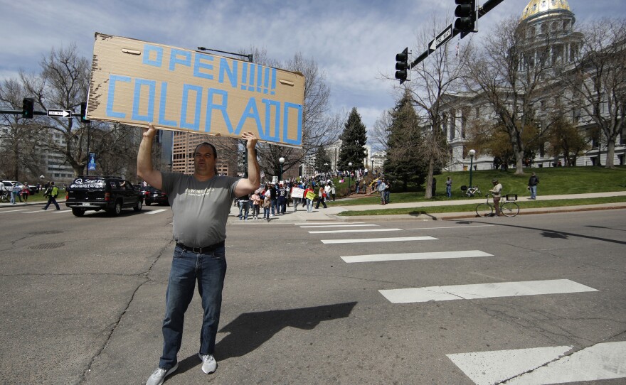 A protester waves a placard during a car protest against the stay-at-home order issued by Colorado Gov. Jared Polis to stem the spread of the new coronavirus on April 19 in Denver.