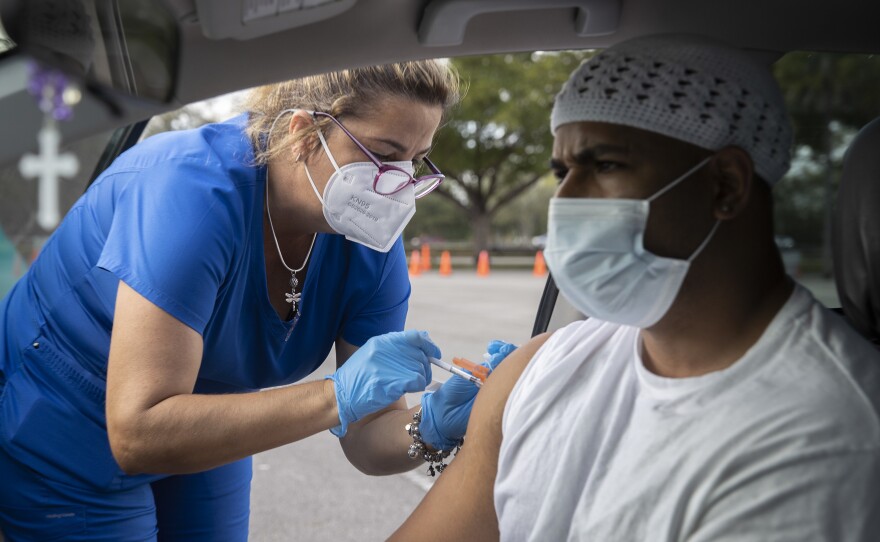 Alejandro Brown receives a COVID-19 vaccine from a health care worker at a drive-thru site in Miami on Dec. 16.