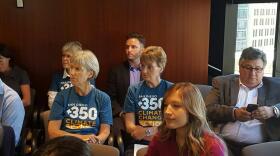 Members of the environmental group San Diego 350 watch the SANDAG board meeting on the regional transportation plan, Oct. 9, 2015.
