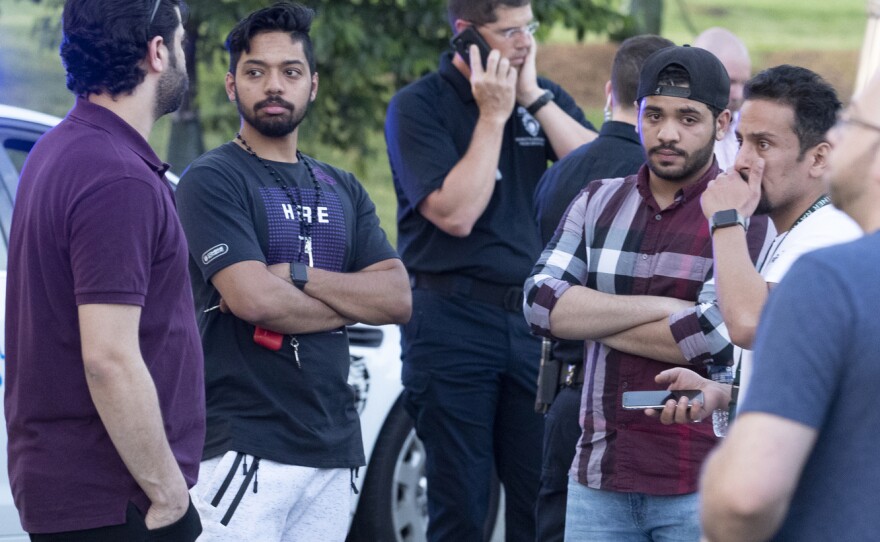 People gather across from the campus of the University of North Carolina, Charlotte after a shooting at the school on Tuesday.