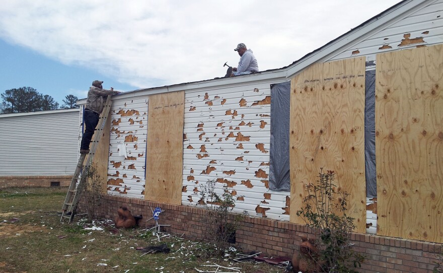 A homeowner secures tarps on the roof of his house in Pearl, Miss., to cover up damage from a hailstorm. Hail broke windows, shattered siding and left holes in his roof.