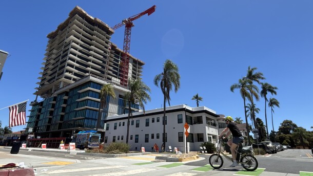 A cyclist rides by the construction site of a high-rise apartment building in Banker's Hill, July 25, 2025.