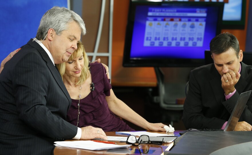 WDBJ-TV news morning anchor Kimberly McBroom, center, gets a hug from visiting anchor Steve Grant, left, as meteorologist Leo Hirsbrunner reflects after their early morning newscast at the station on Thursday.
