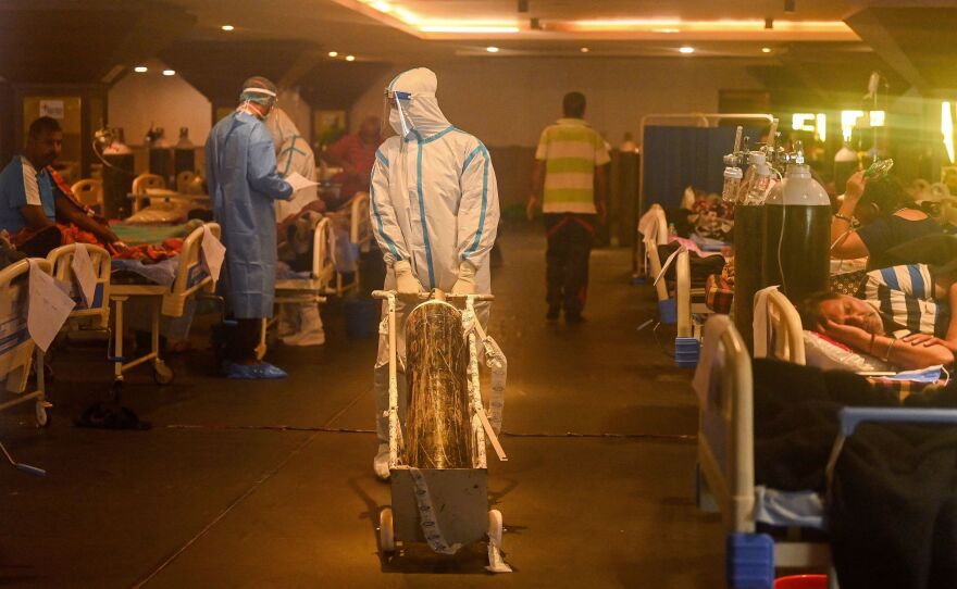 Health workers in protective gear tend to patients Wednesday in a banquet hall temporarily converted into a COVID-19 care center in New Delhi.