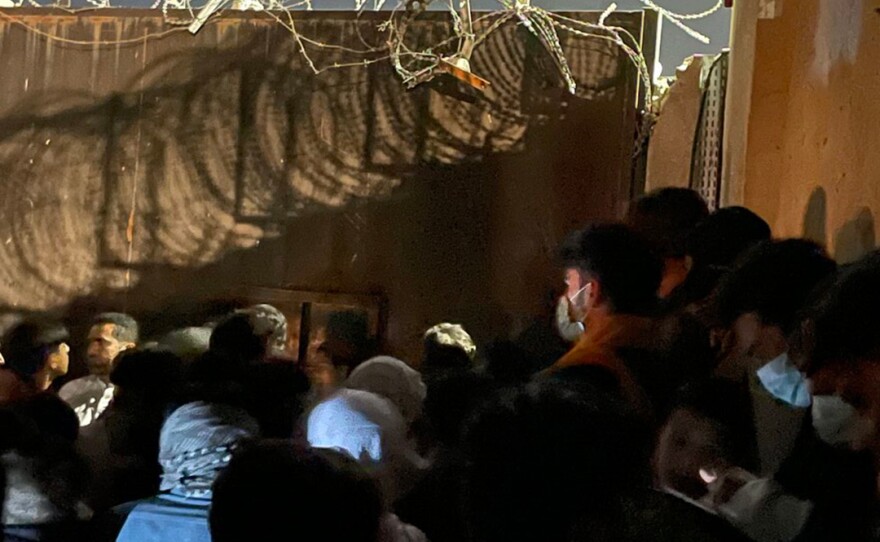 People waiting outside of a gate at the Kabul airport.