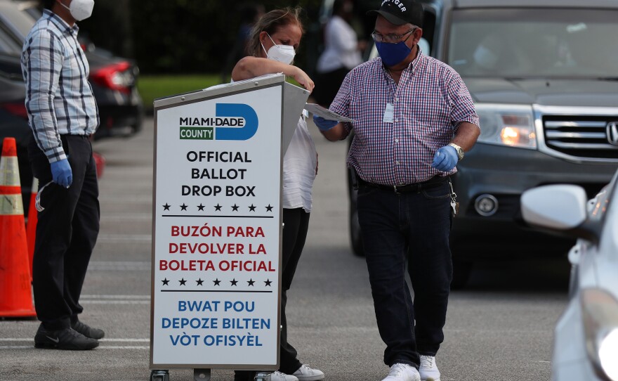 Poll workers at the Miami-Dade County Elections Department deposit returned mail-in ballots into an official ballot drop box on primary election day on Aug. 18 in Doral, Fla.