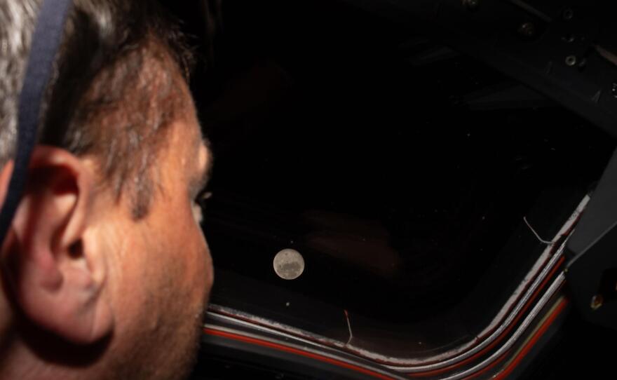 Artemis II commander and NASA astronaut Reid Wiseman looks out one of the Orion spacecraft's main cabin windows at the moon ahead of the crew's lunar flyby. After successfully looping around the moon, the space capsule is now headed back toward Earth.
