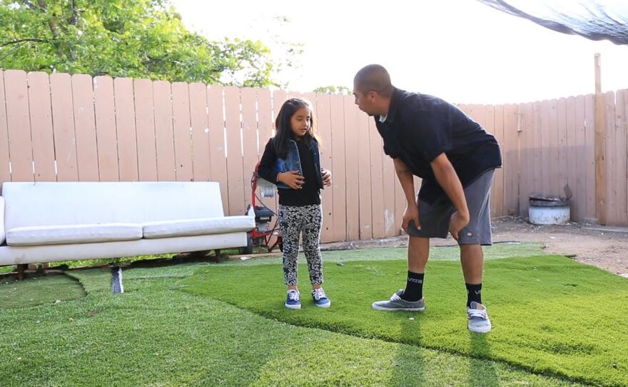 Victorugo Rodriguez Tello plays with his daughter in their backyard, May 22, 2015.