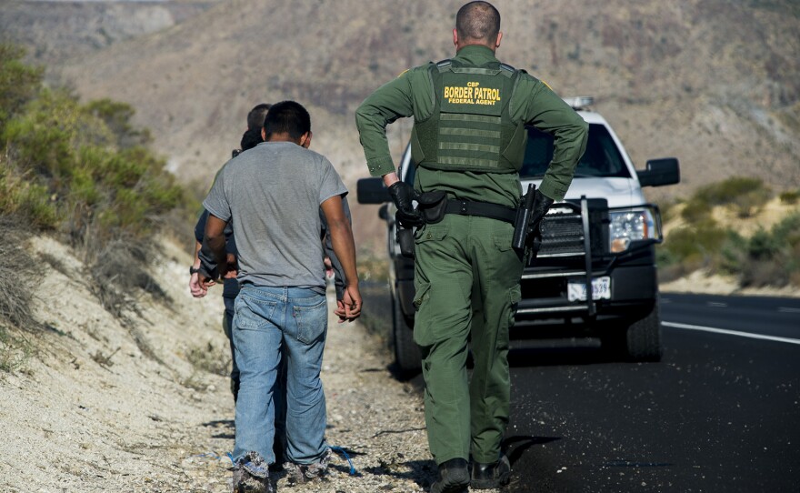 A Border Patrol agent detains three men along Interstate 8 near the U.S.-Mexico border in eastern San Diego County on Sept. 5, 2017.