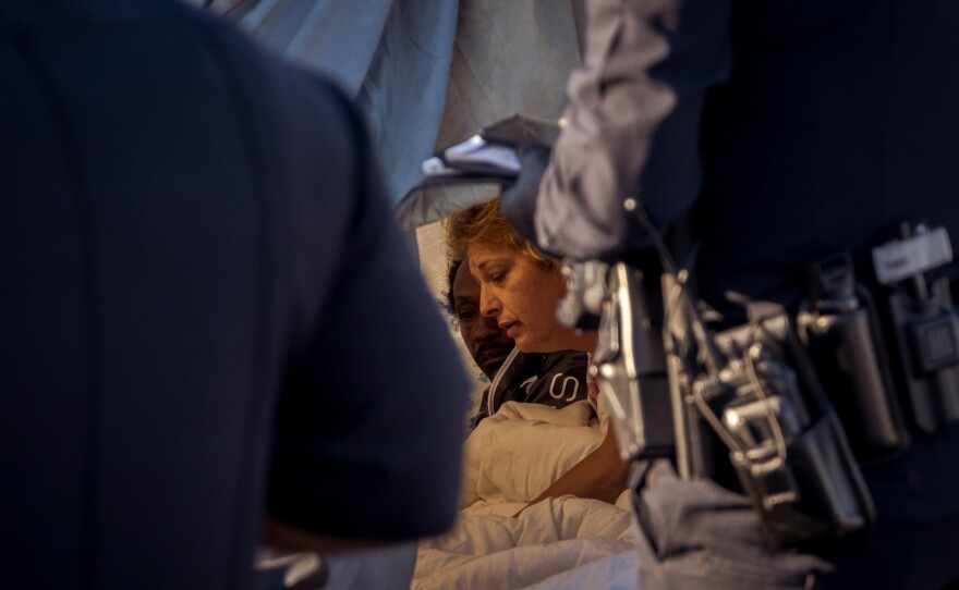 A couple living in a tent at a homeless encampment on Sports Arena Boulevard in San Diego's Midway District is awoken by San Diego Police Officers beginning their enforcement of the City of San Diego's anti-encroachment and illegal lodging laws, February 14, 2022.