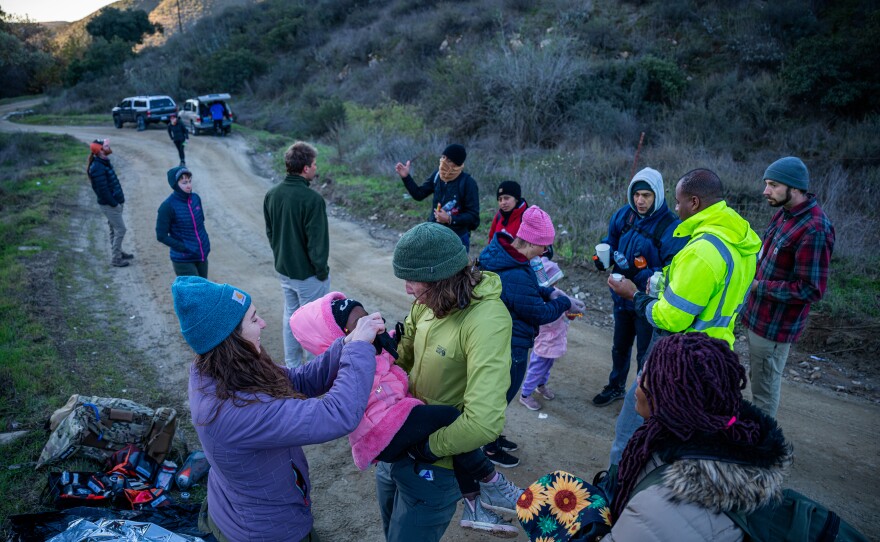 A toddler is assisted by members of humanitarian group Borderlands Relief Collective. One of the major concerns in the rugged terrain that separates Tijuana from San Diego is hypothermia.