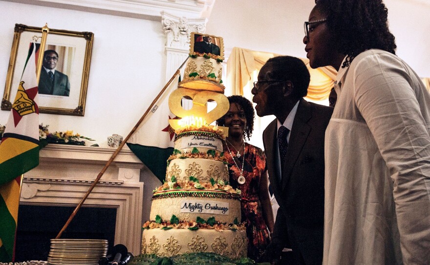 Zimbabwe President Robert Mugabe, flanked by his wife Grace Mugabe (left) and daughter Bona (right), blows candles on his cake during a surprise birthday party at the Statehouse in Harare, on Feb. 22. His birthday was Feb. 21; he held a massive celebration Saturday.