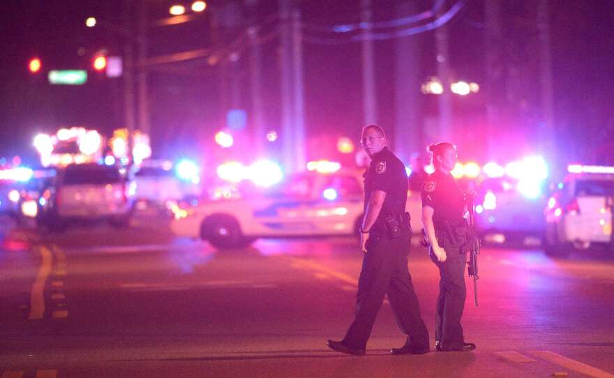 Police officers stand guard down the street from the scene of a deadly mass shooting at the Pulse Orlando nightclub in Orlando, Fla., early in the morning on Sunday. Authorities say at least 50 people died in the attack.