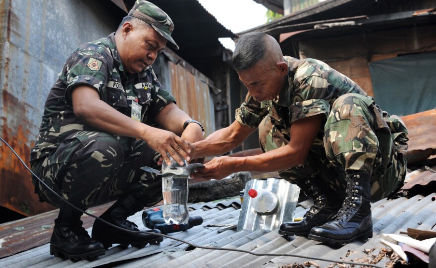 Filipino soldiers install solar light bulbs through a roof in a shantytown in Manila, Philippines. The bulbs are actually old plastic soda bottles filled with water and bleach, and powered by the sun.