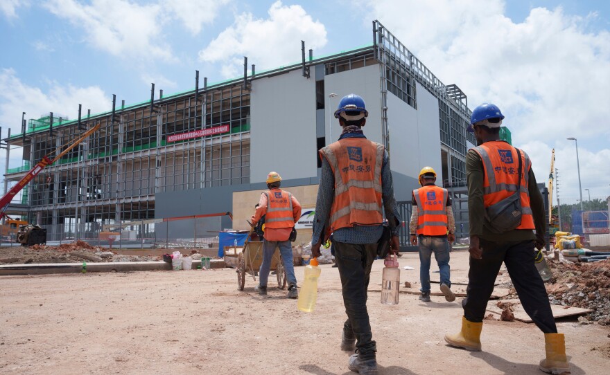 FILE -Construction workers walk to a data center building under construction in Sedenak Tech Park in Johor state of Malaysia, Sept. 27, 2024.