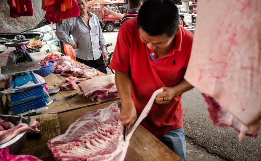 A butcher prepares cuts of meat for customers at a market in Klang. Between 1970 and the late 1990s, Malaysia's pork industry exploded. The pig population tripled to more than 3 million. After the government killed 1 million pigs, the industry nearly collapsed.