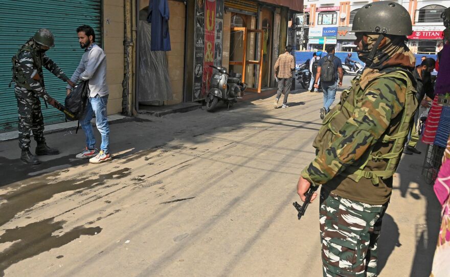 An Indian paramilitary trooper checks a man's bag during a random search along a street in Srinagar on Tuesday.