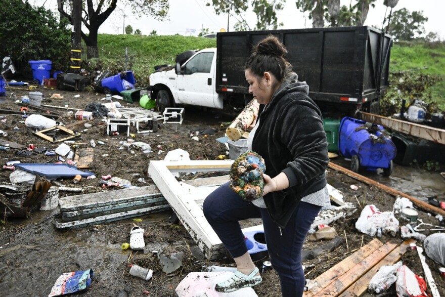 Marlene Sanchez-Barriento salavages items behind her home damaged by flooding, Tuesday, Jan. 23, 2024, in. Sanchez-Barriento's home was damaged when flood waters rushed though her home on Monday, Jan. 22. 