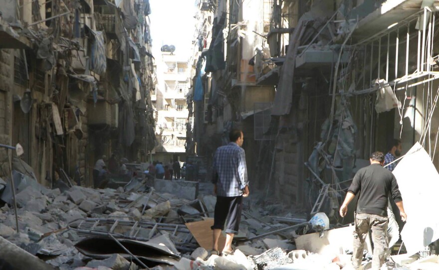 In a photo provided by the Syrian Civil Defense group known as the White Helmets, men inspect damaged buildings in Aleppo, Syria, on Saturday.