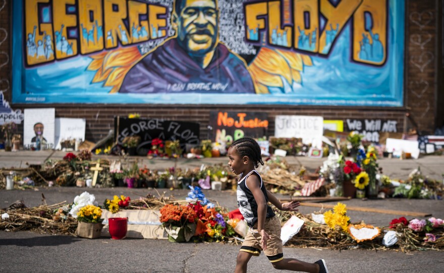 The Minnesota Legislature has approved a bill to revise rules on police use of force in response to the killing of George Floyd. Here, a boy runs past a mural at a memorial to Floyd outside Cup Foods.