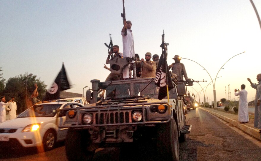 Militants from the Islamic State parade in a commandeered Iraqi security forces armored vehicle on a main street in Mosul, Iraq, in June 2014.