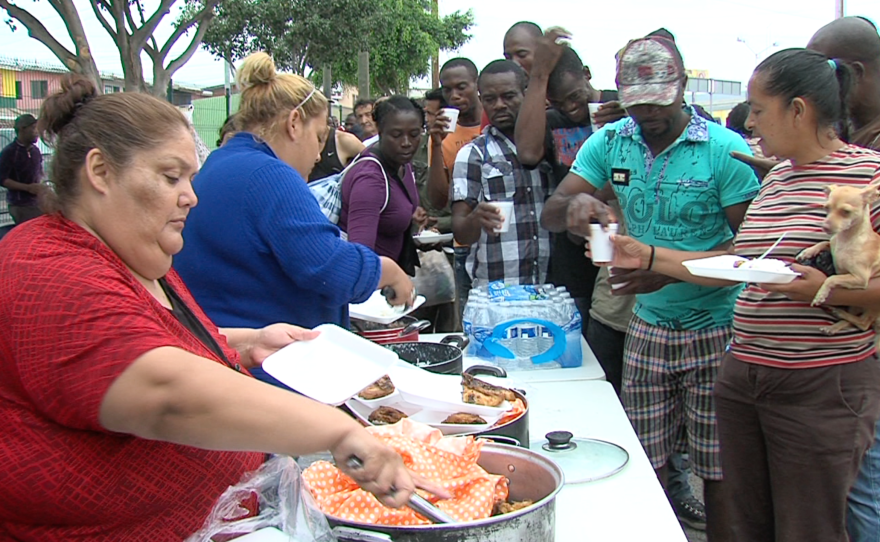 Haitian and African migrants line up for fried chicken, rice and beans in Tijuana, Sept. 19, 2016.