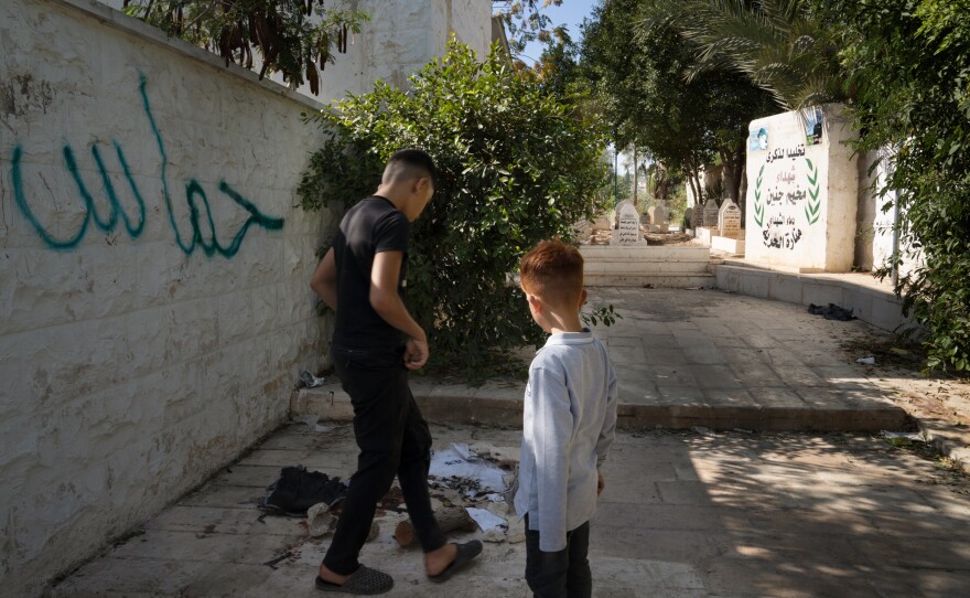 Boys look at a ripped T-shirt and blood on the ground at the site of an Israeli drone strike that killed two teenagers and one 20-year-old in Jenin refugee camp.