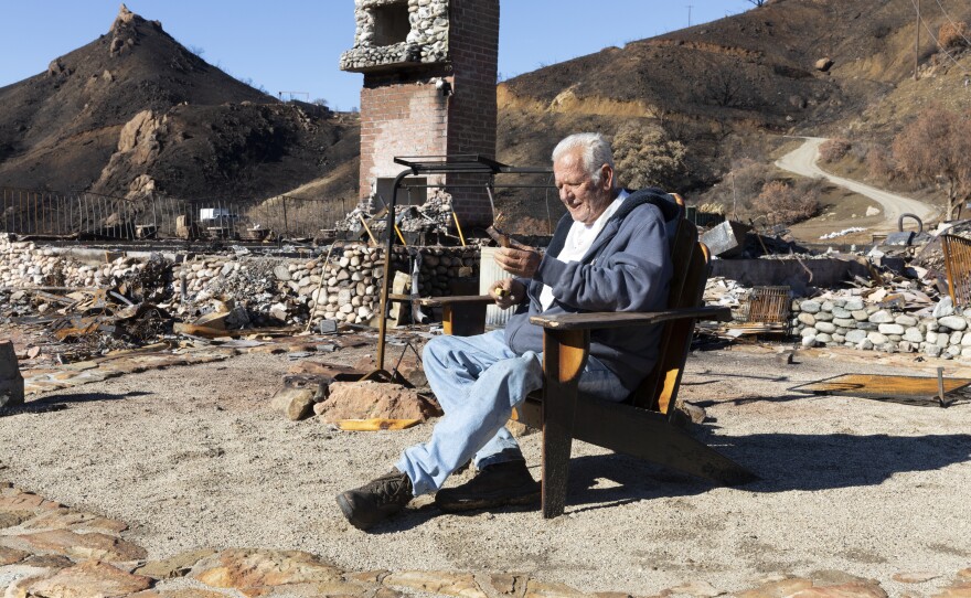 Holding a cigar, Gary Jones sits where his house once stood, in a wooden porch chair that somehow wasn't destroyed. Jones lost three of his five dogs in the flames and came back the next day to bury them. His horse was found alive up the hill and is recovering from burns.