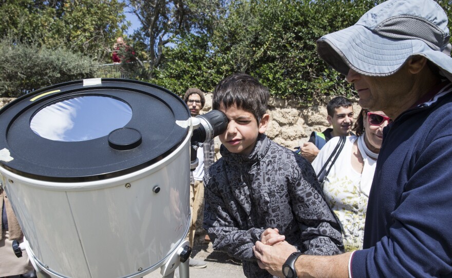 A young astronomer uses a telescope to catch a glimpse of the partial solar eclipse in Tel Aviv.