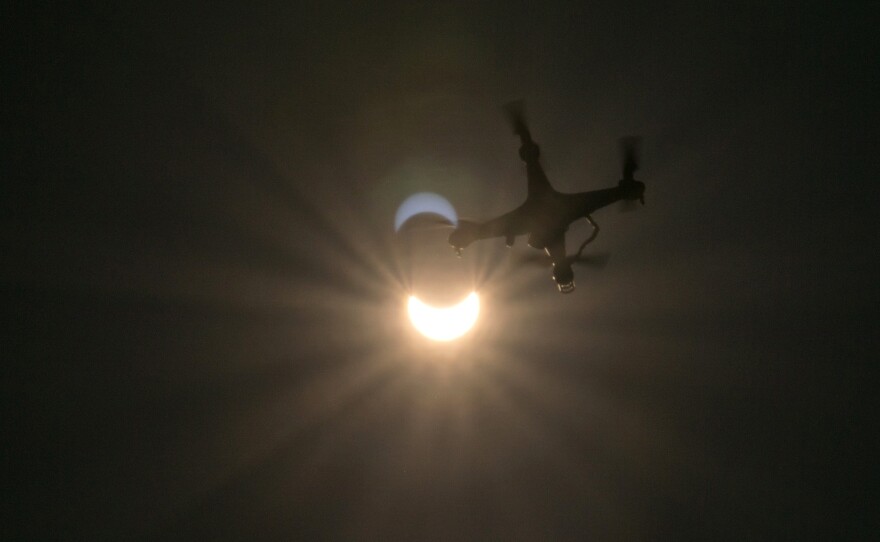 A drone flies in foreground of the partial eclipse in Vienna.