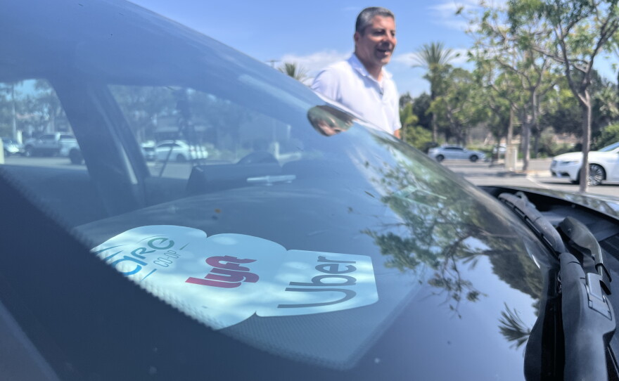 Rideshare driver and co-founder of San Diego Drivers United Librado Rivera walks next to his work car, Aug. 10, 2026.
